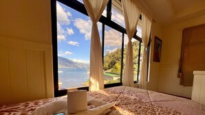 A bedroom with a large window offering a view of a lake and mountains. - Hotel Casa Ki'iil San Juan La Laguna  (San Juan La Laguna)