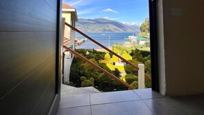A view from a room with a large window overlooking a scenic landscape with mountains, a body of water, and a dock. - Hotel Casa Ki'iil San Juan La Laguna  (San Juan La Laguna)