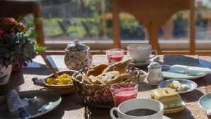 Una mesa de desayuno con diferentes alimentos y una taza de café, con una vista panorámica de montañas al fondo.