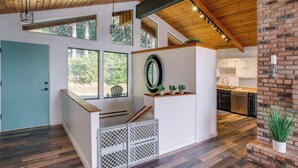 Une cuisine moderne avec un plancher en bois, une cuisinière encastrée et un mur d’accent en briques.