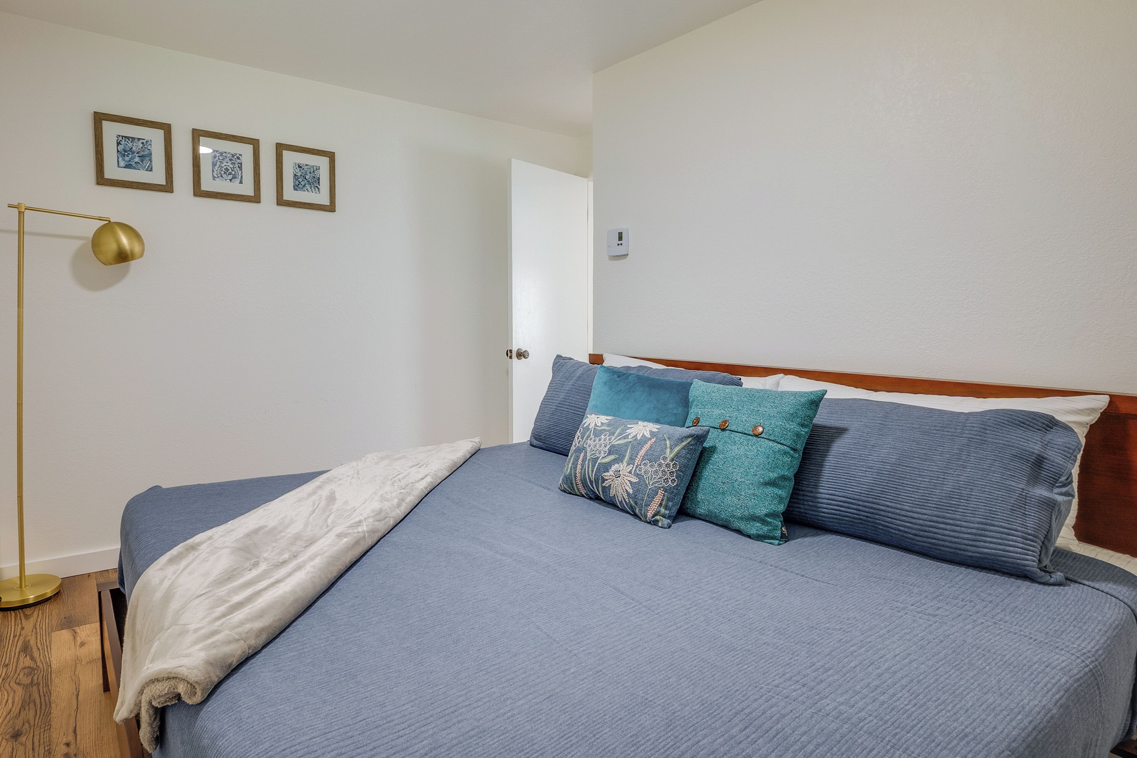 Un dormitorio con una cama, una lámpara de noche y tres cuadros en la pared.