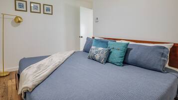Un dormitorio con una cama, una lámpara de noche y tres cuadros en la pared.