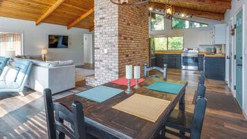 A spacious dining area with a wooden table, chairs, and a brick column.