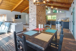 A spacious dining area with a wooden table, chairs, and a brick column. - Tree-Lined Gold Beach Retreat w/ Multiple Decks! (Gold Beach)