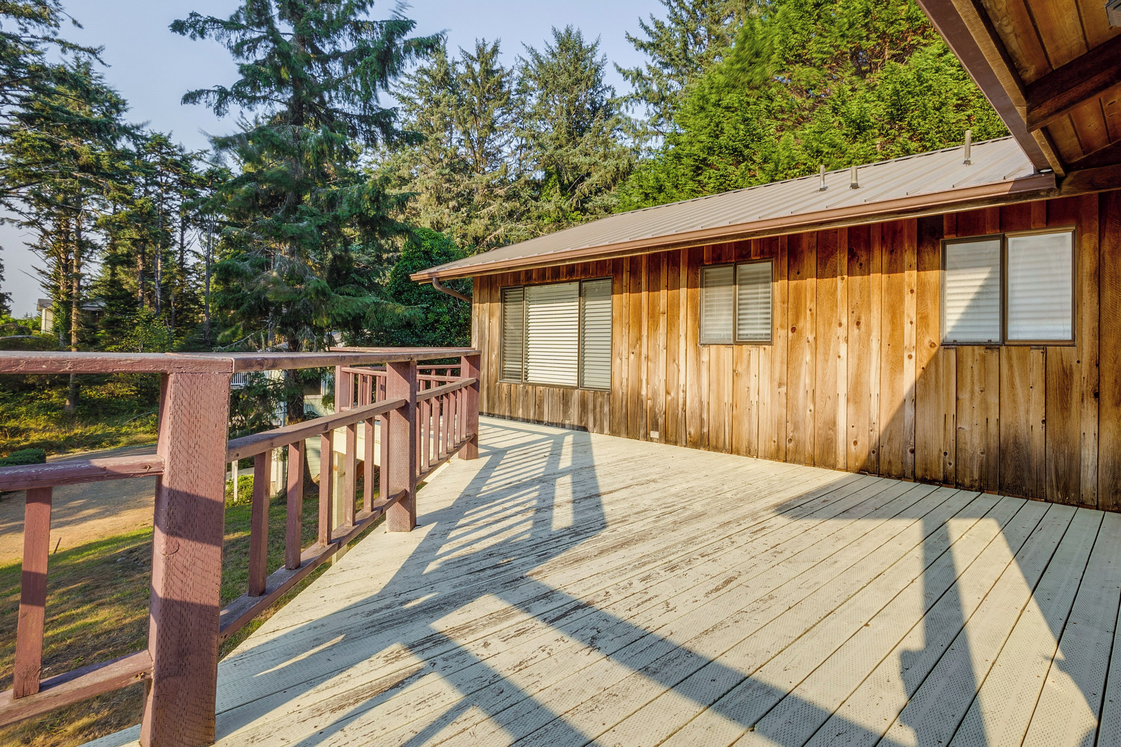 A wooden cabin with a deck, surrounded by trees.