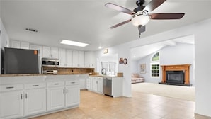 A spacious kitchen with white cabinets, a built-in oven, and a dishwasher. There is a ceiling fan and a fireplace in the adjacent living area. - Casa De for 8people/3BD 3BA, 10people/3BD 4BA,+12people/4BD 4BA (Thousand Oaks)