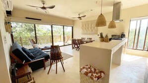 A spacious living area with a sofa, dining table, and chairs, a kitchen with a large island, and a ceiling fan. - RELAX TULUM apartment, 2 bedrooms with a huge 4000 ft rooftop, pools, BBQ, and jungle view (Tulum)