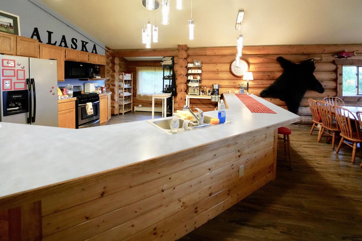 A spacious kitchen with wooden cabinets, a large island with a sink, and a dining area with wooden chairs.