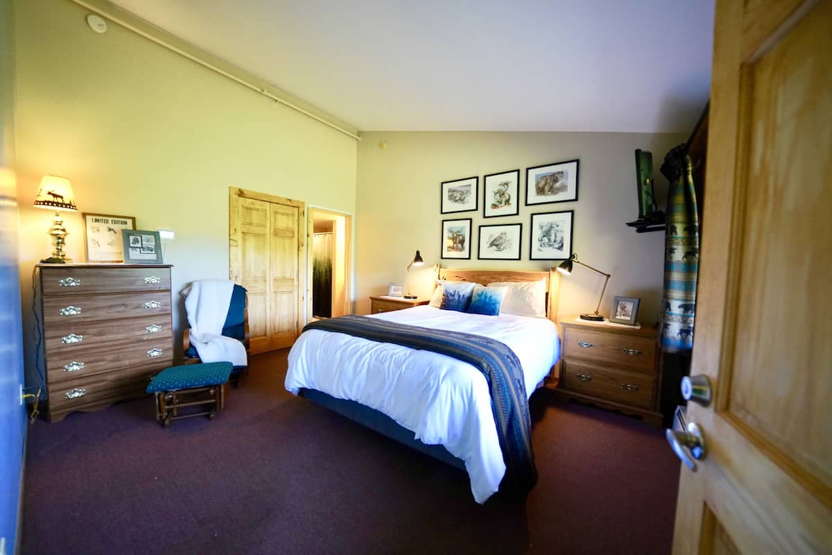 A bedroom with a bed, a dresser, a chair, a nightstand, and a door.