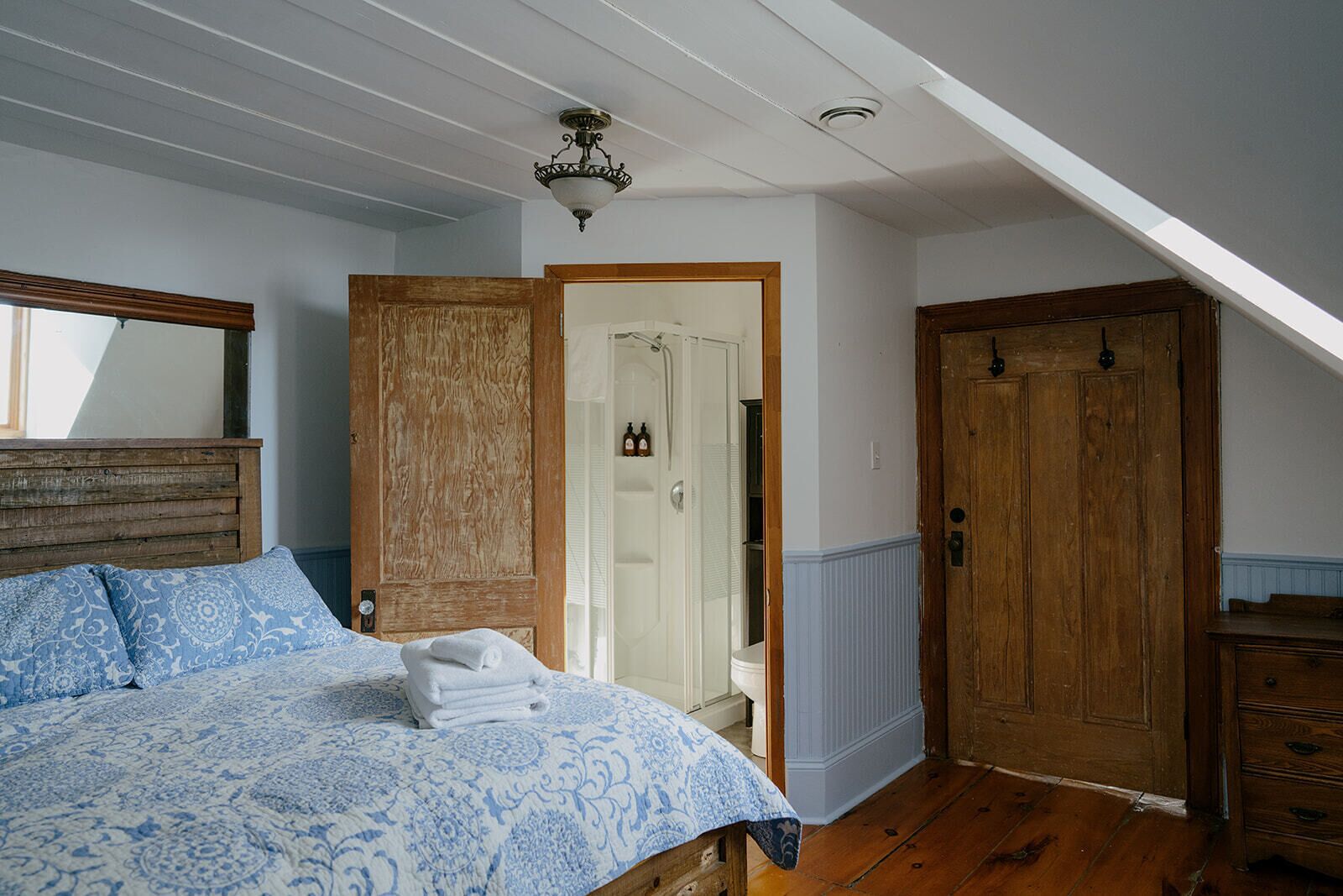 A bedroom with a bed, wooden wardrobe, and a door leading to a bathroom.