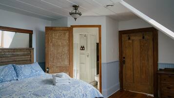 A bedroom with a bed, wooden wardrobe, and a door leading to a bathroom.