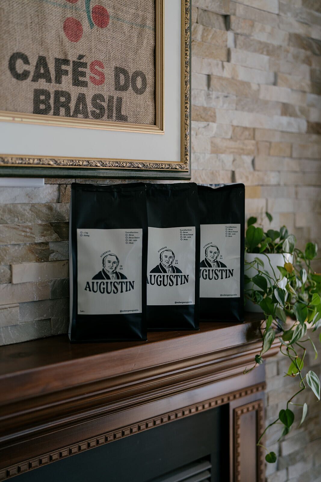 Tres maletas con la etiqueta 'Augustin' sobre una repisa con una obra de arte enmarcada encima.