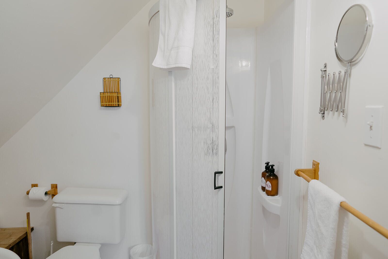 A bathroom with a toilet, shower, and a towel rack.