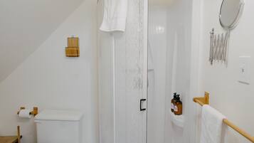 A bathroom with a toilet, shower, and a towel rack.