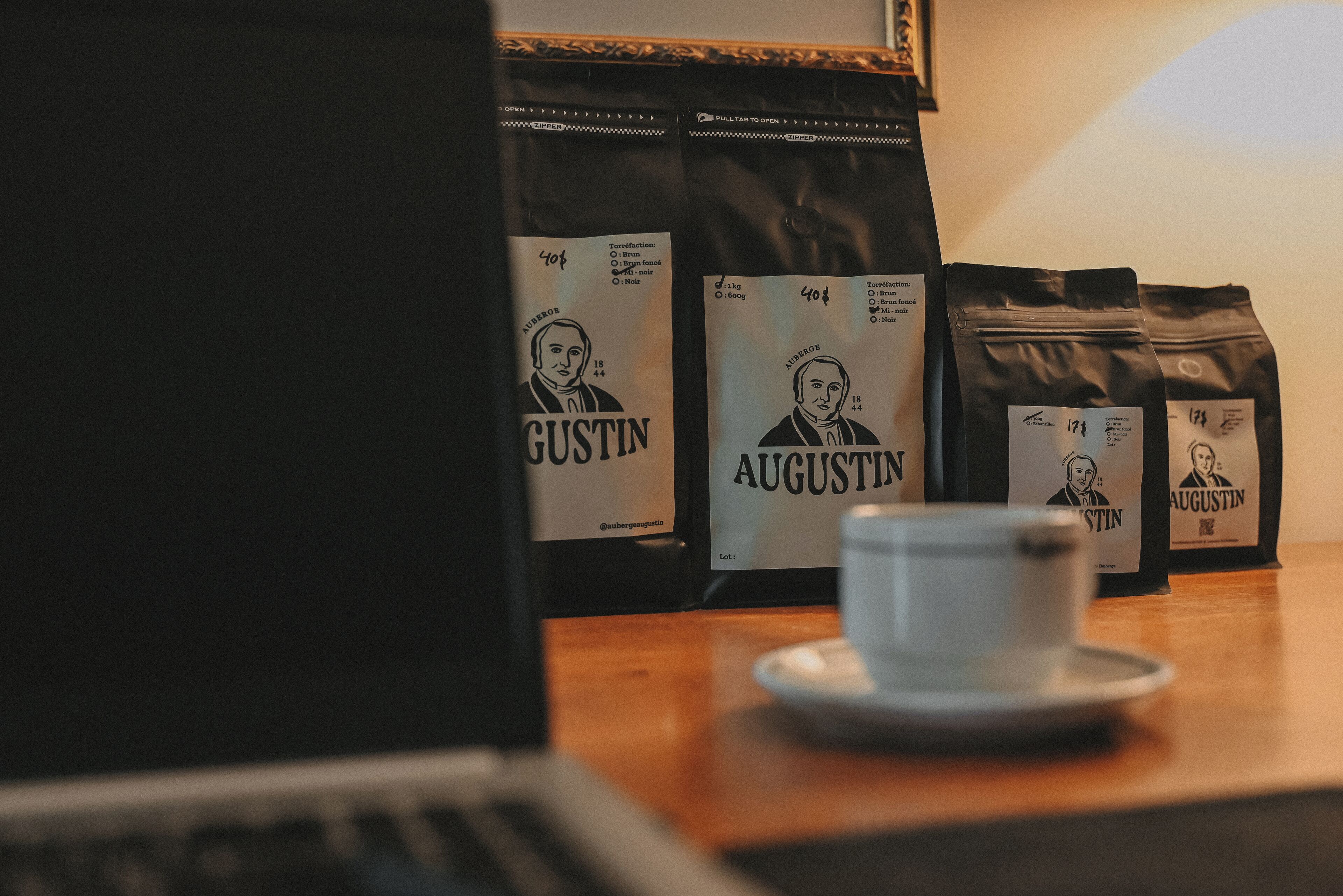 A table with coffee bags labeled 'Augustin' and a cup of coffee.