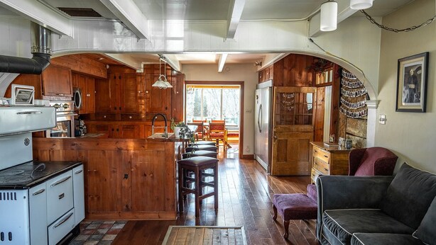 Un'ampia cucina con mobili in legno, un'isola centrale e un'area pranzo con divano e poltrone.