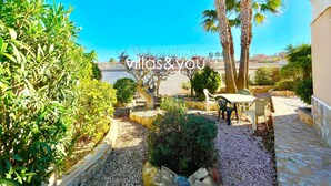 A courtyard with a stone pathway, palm trees, and outdoor seating.
