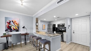 A modern kitchen with a central island, bar stools, and a dining area with a table and chairs.