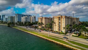 A coastal cityscape with modern high-rise buildings, a marina, and a well-maintained promenade.