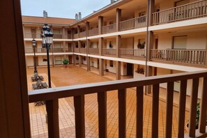 Un immeuble à plusieurs étages doté de balcons, d’une cour dallée et d’un lampadaire.