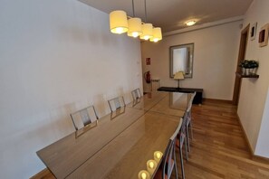 Une salle de conférence moderne, dotée d’une longue table, de chaises et d’un luminaire au plafond.