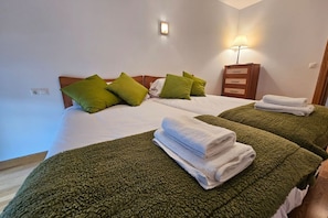 A hotel room with two beds, green and white bedding, a nightstand with a lamp, and a wall-mounted light. - 13B01 Apartment with Garage and Terrace by R2R (Ribadesella)