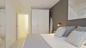 Ein Schlafzimmer mit Bett, Nachttischen, einem Kleiderschrank und einer Wandlampe.