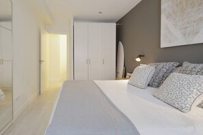 Ein Schlafzimmer mit Bett, Nachttischen, einem Kleiderschrank und einer Wandlampe.