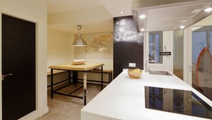 Eine moderne Küche mit weißer Arbeitsplatte, einem Holztisch und einer Karte an der Wand.