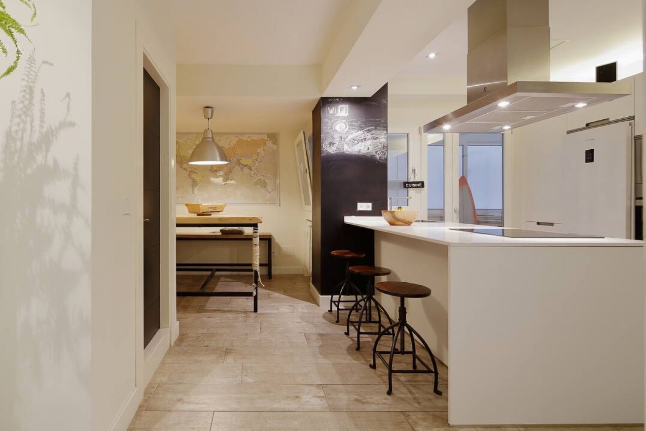 A modern kitchen with a bar area, a map on the wall, and a pendant light.