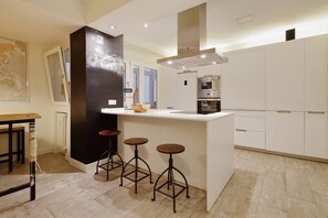 Una cocina moderna con una isla central, taburetes de bar, horno empotrado y un mapa en la pared.