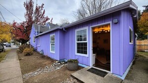 Une maison de plain-pied à l’extérieur violet, dotée d’un porche et d’une porte de garage bien visible.