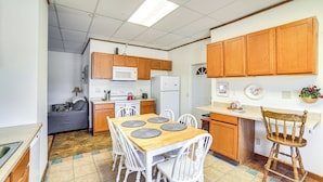 A compact kitchen with wooden cabinets, a dining table with white chairs, a microwave, and a refrigerator. - 2 Mi to Ice Caves: Pet-friendly Eben Junction Apt (Eben Junction)