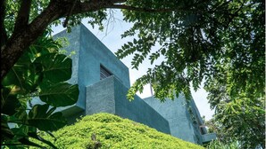 Un bâtiment moderne au design géométrique original, entouré d’une végétation luxuriante.