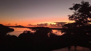A sunset view over a body of water with trees in the foreground. - Local Paradisíaco NA Ilha DA Magia Loft Arcano Maior (Lagoa da Conceição Florianópolis)