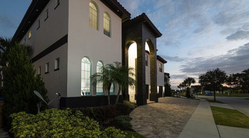 A modern building with a stone facade, large arched windows, and a landscaped courtyard.