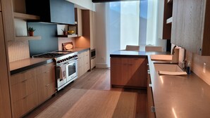 Una cocina moderna con armarios de madera, una estufa y un amplio ventanal que proporciona luz natural.