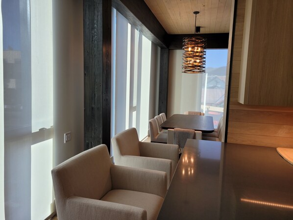 A modern interior with a long bar, cushioned seating, and a hanging light fixture. - Downtown Ketchum Condo (Ketchum)