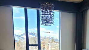 Una sala de estar moderna con un sillón de cuero marrón, una mesa de centro de madera y vistas a las montañas a través de amplios ventanales.