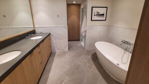 Un baño moderno con dos lavamanos, una bañera grande y una puerta de madera.