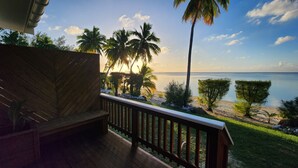 A wooden deck with a railing overlooking a beach with palm trees and a view of the ocean. - Resort Tava'e (Aitutaki)