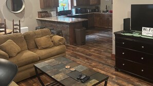 A living room with a sofa, coffee table, and a TV stand with a Wi-Fi sign. - Family size Barndo,  Side by Side friendly......Lots of Trails to explore. (Sunbright)