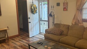A living room with a wooden herringbone floor, a sofa, a coffee table, and a door leading to a balcony. - Family size Barndo,  Side by Side friendly......Lots of Trails to explore. (Sunbright)