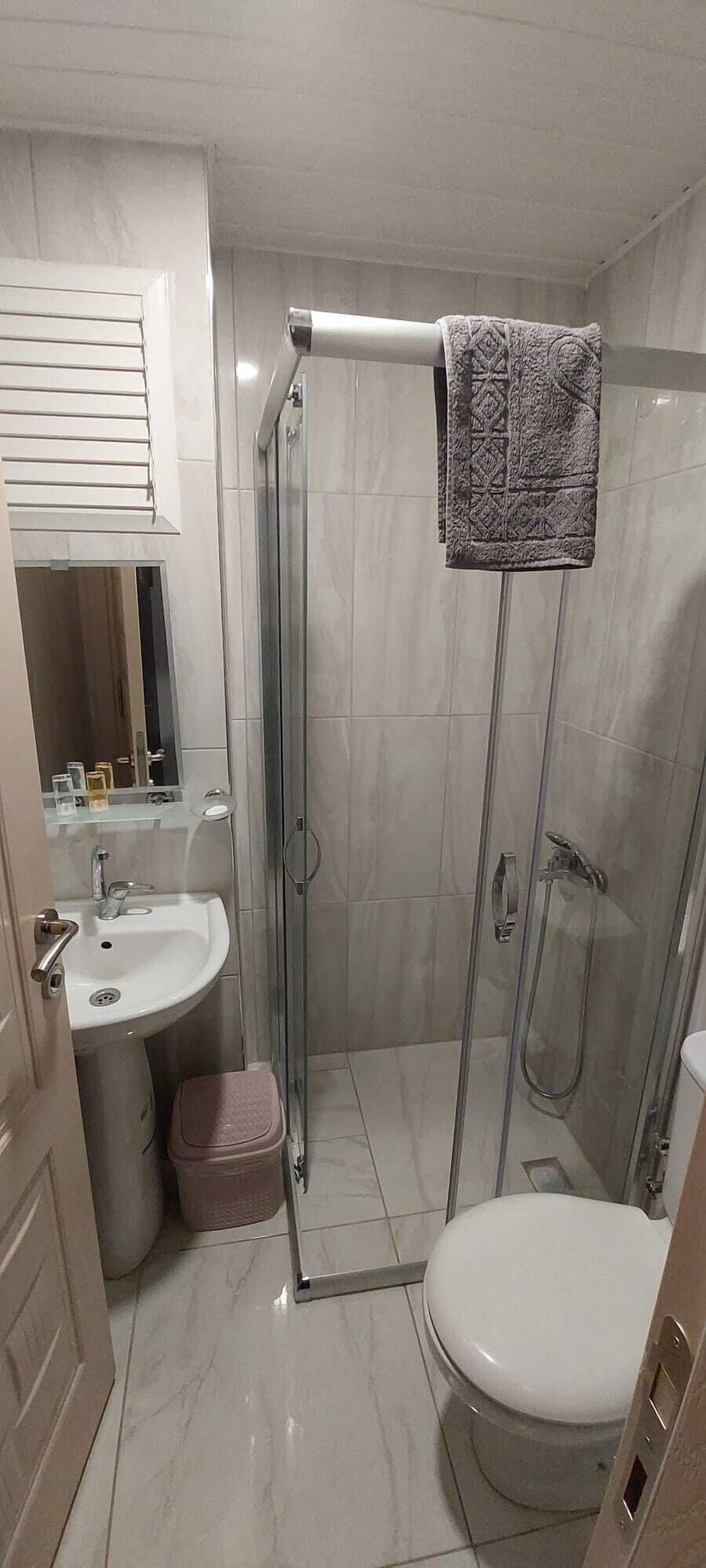 Un baño con ducha envuelta en vidrio, inodoro, lavabo y espejo.