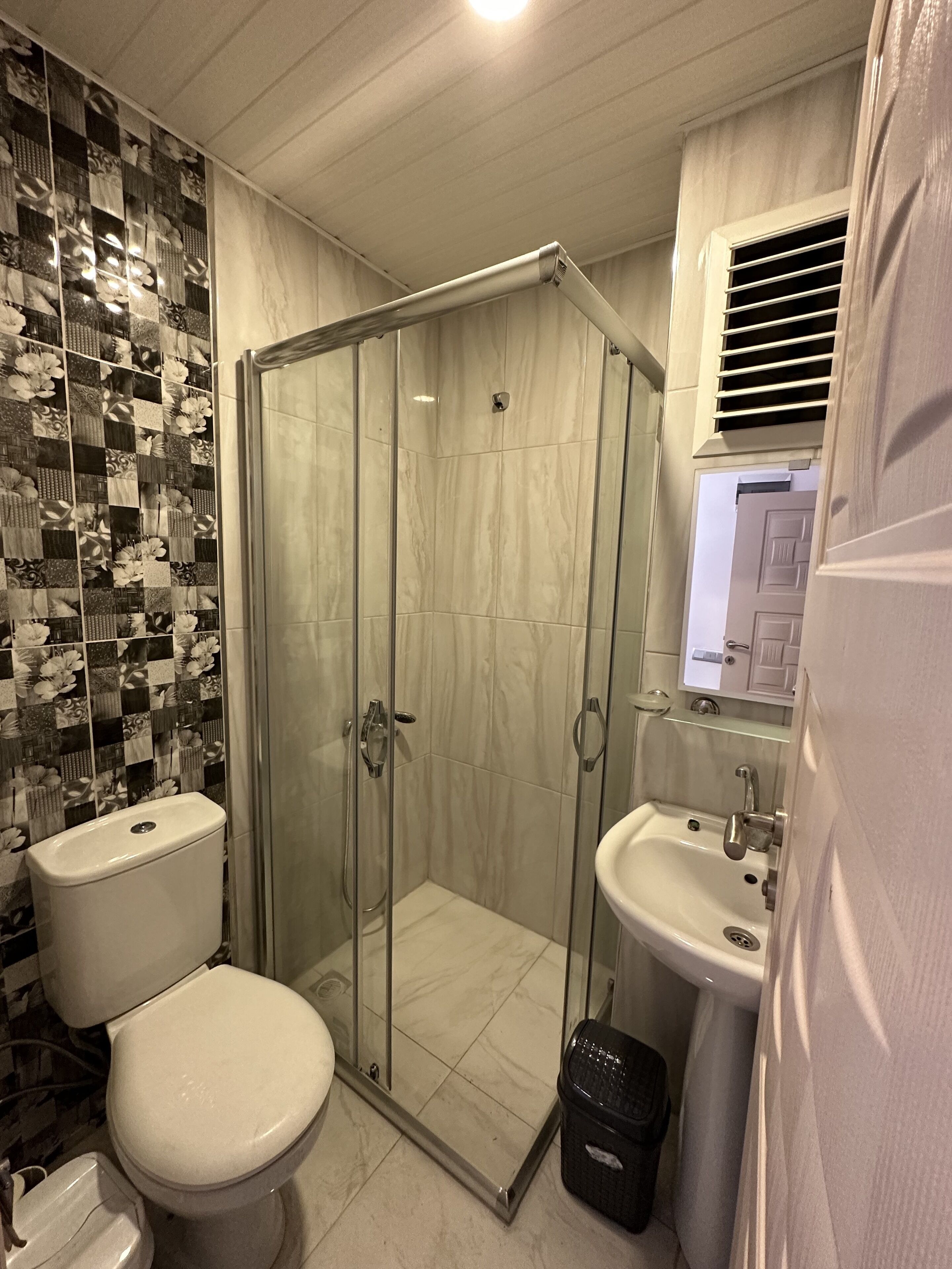 Un baño con inodoro, ducha de vidrio y lavamanos.
