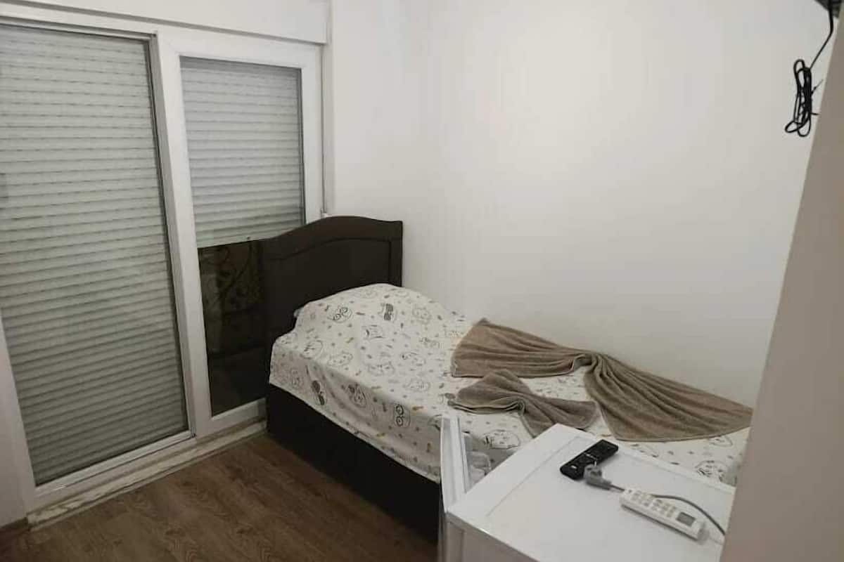 A small room with a bed, a desk, and a sliding door.