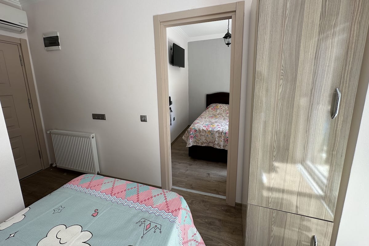 A bedroom with a bed, a wardrobe, a radiator, and a door leading to another room.