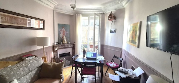 A room with a fireplace, a dining table with chairs, a sofa, and a television.