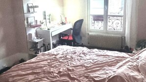 Makuuhuoneessa on sänky, työpöytä, tuoli ja ikkuna, josta on näkymä rakennuksiin.