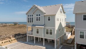 A two-story beachfront house with a balcony, a covered porch, and a view of the ocean. - The Tides by KEES Vacations (Kill Devil Hills)